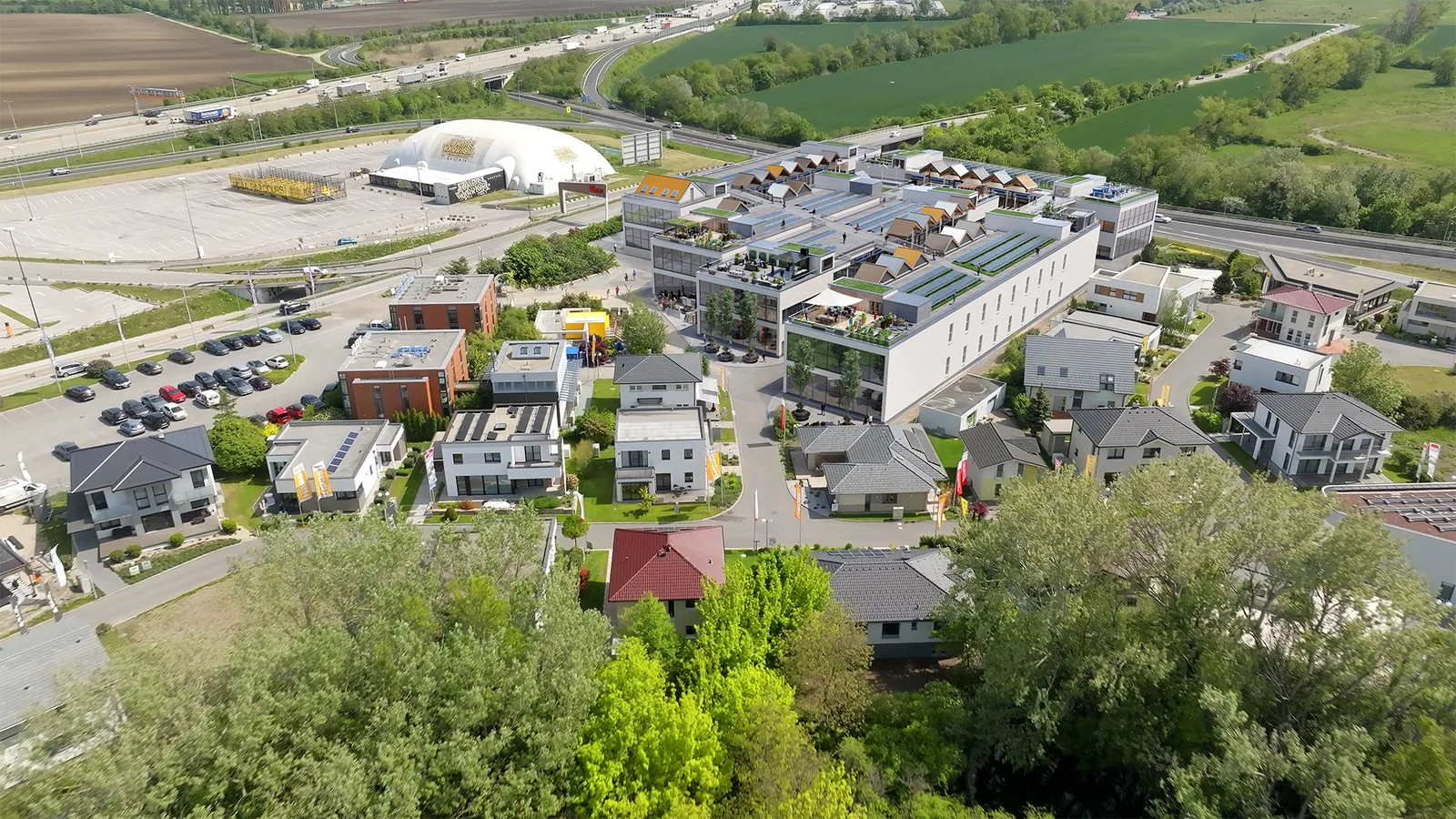 Ausgearbeitete Projektvisualisierung des Gebäudekomplexes mit gestalteten Dachflächen im bestehenden Umfeld aus der Vogelperspektive